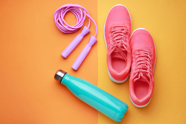 Sports water bottle, shoes and jumping rope on color background - Fotoğraf, Görsel