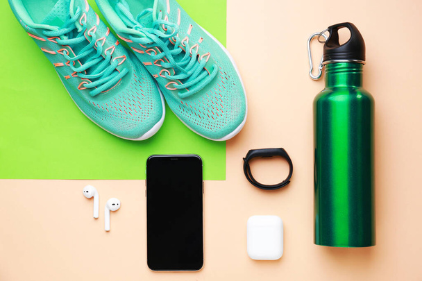 Sports water bottle, shoes, mobile phone and gadgets on color background - Photo, Image