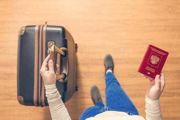 Вид сверху на девушку с чемоданом и российским паспортом, идущую по аэропорту на паспортный контроль
. - Фото, изображение