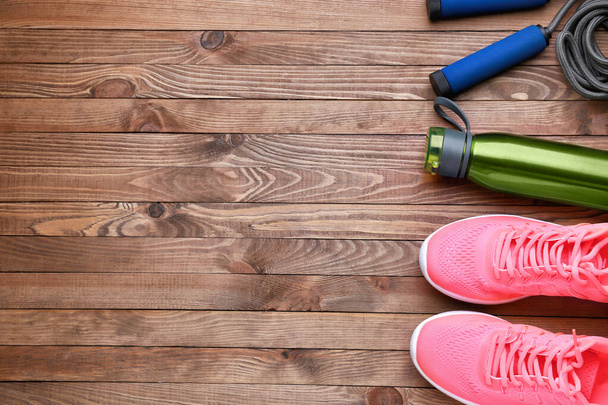 Sports water bottle, shoes and jumping rope on wooden background - Photo, Image