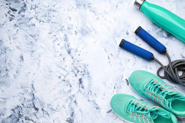 Sport waterfles, schoenen en springtouw op witte achtergrond - Foto, afbeelding
