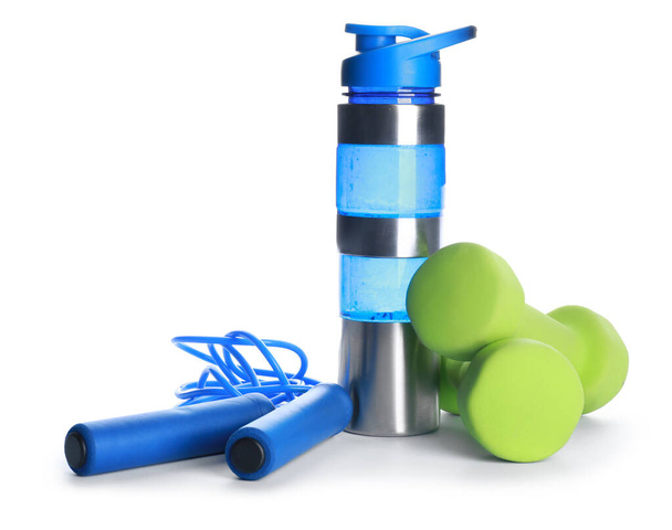 Sports water bottle, dumbbells and jumping rope on color white - Photo, Image