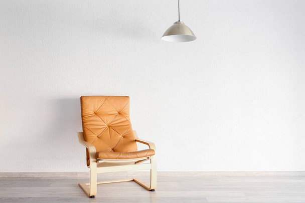 Stylish armchair with lamp near white wall - Fotó, kép