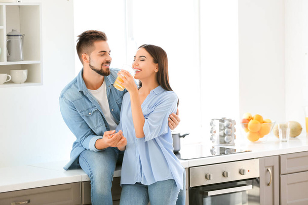 Beau jeune couple buvant du jus dans la cuisine à la maison
 - Photo, image