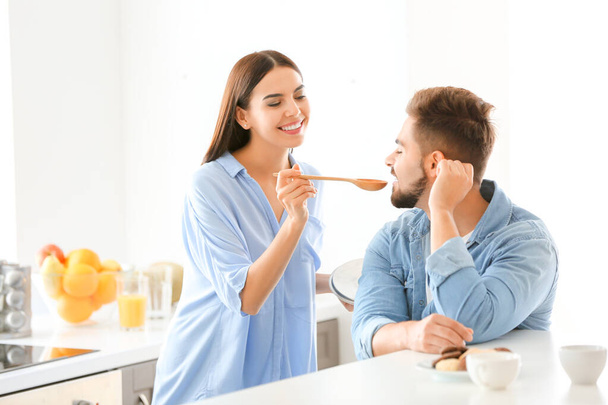 Beautiful young couple cooking together in kitchen at home - Foto, afbeelding