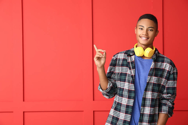 Афроамериканський підліток вказує на щось на кольоровому фоні - Фото, зображення