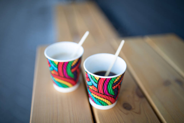 Желтые и красные одноразовые бумажные стаканчики с кофе близко к светлой древесины
. - Фото, изображение