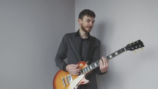 Young man with electric guitar playing and preparing for concert. Handsome man with beard holding guitar and playing rock and blues songs. - Πλάνα, βίντεο