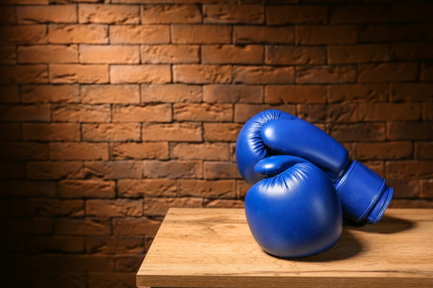 Pair of boxing gloves on table against brick wall - Photo, Image
