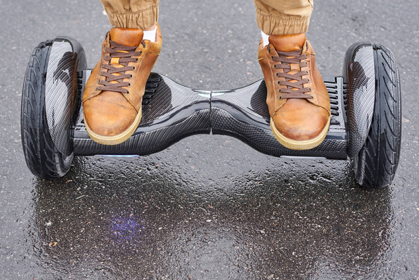 Κοντινό πλάνο του ανθρώπου χρησιμοποιώντας hoverboard σε ασφαλτοστρωμένο δρόμο. Πόδια σε electr - Φωτογραφία, εικόνα