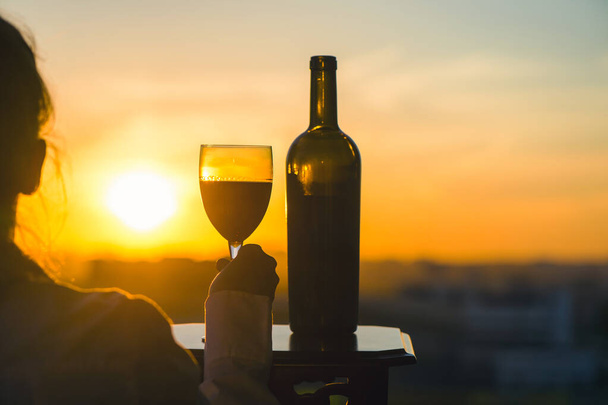 female hand with wine glass on sunset background.  - Foto, Imagen