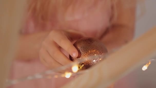 Ένα εννιάχρονο κορίτσι στη διακόσμηση της Πρωτοχρονιάς κρατά ένα παιχνίδι της Πρωτοχρονιάς στα χέρια της. Νέο έτος 2020. - Πλάνα, βίντεο