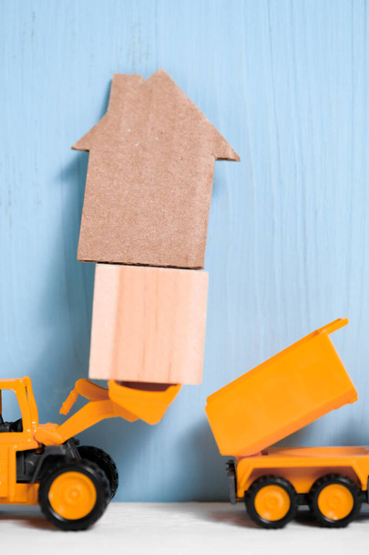 Pelle jouet orange charge cube en bois et maison en carton à l'arrière du camion
. - Photo, image