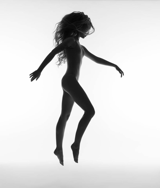 Meisje met lang haar springen. silhouet van de vrouw. - Foto, afbeelding
