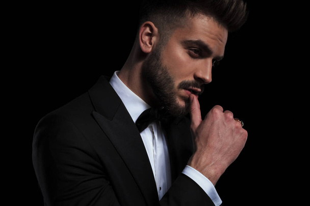 businessman wearing black tuxedo seductively touching lips - Photo, Image