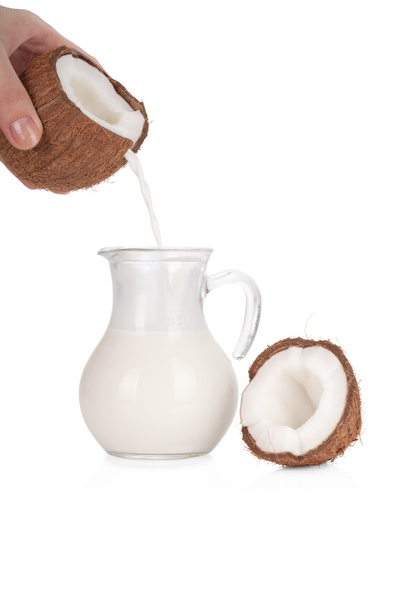 Woman's hand pouring coconut milk into a jar isolated on white - Фото, изображение