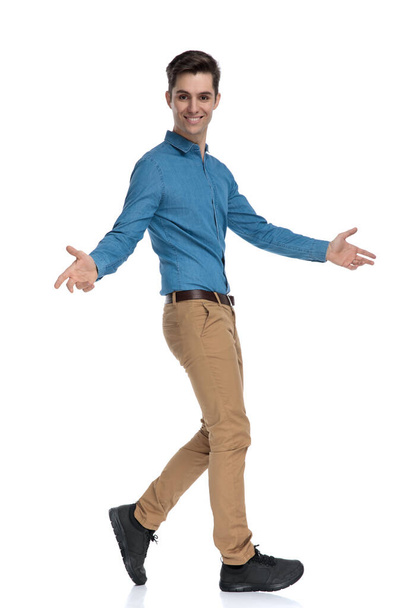 side view of happy young man walking and opening arms - Foto, afbeelding