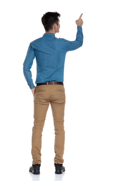 back view of smart casual man in blue shirt pointing finger - Foto, Imagen