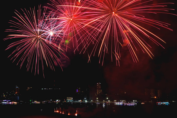 Vibrant red fireworks splashing in the city's night sky - Photo, Image