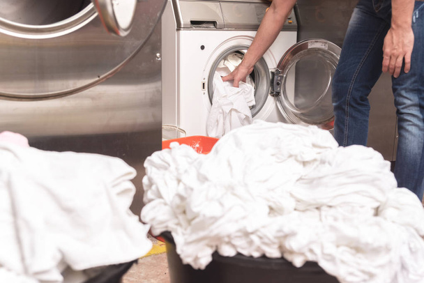 Toma de mano masculina de la ropa limpia de la lavadora
 - Foto, imagen