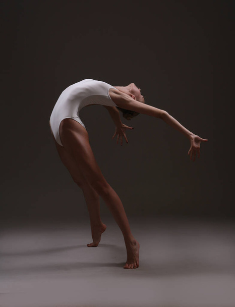 Ευέλικτη κοπέλα που χορεύει σε λευκό κορμάκι - Φωτογραφία, εικόνα