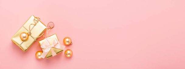 Cajas festivas con lazo de satén bolas de juguete dorado un fondo rosa pastel. Disposición plana. Concepto de vacaciones. Copiar espacio
. - Foto, Imagen