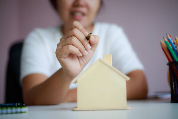 Gelukkige Aziatische vrouw met potlood gelijkspel en plan met houten huis p - Foto, afbeelding