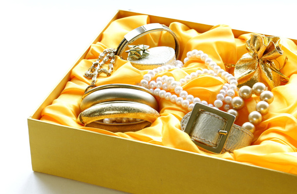Kultakorut ja helmet keltaisessa lahjapakkauksessa
 - Valokuva, kuva