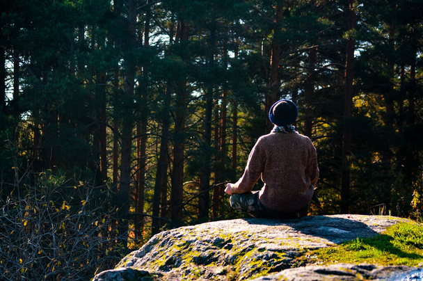 Man in a sweater meditates on a rock. - Fotoğraf, Görsel