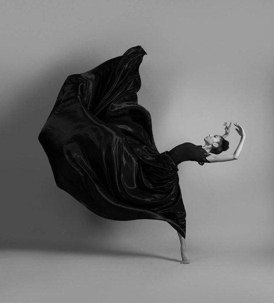 Ballerina dansen in zwart vliegende jurk - Foto, afbeelding