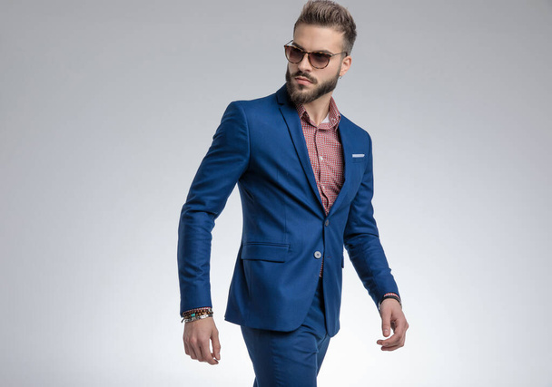 cool moda facet w niebieski garnitur Walkind i pozowanie - Zdjęcie, obraz