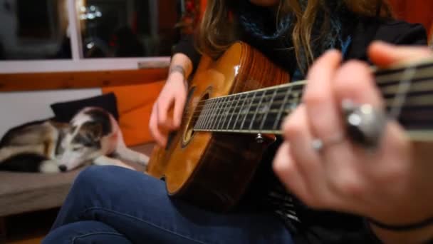 Dziewczyna gra na gitarze w salonie. - Materiał filmowy, wideo