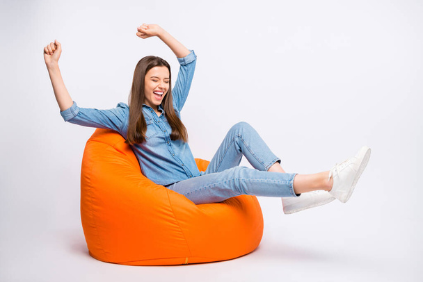 Profile side photo of delighted funky girl have rest sit big lounge armchair watch football world cup match see team win raise fists scream yeah wear casual outfit isolated white color background - Foto, afbeelding