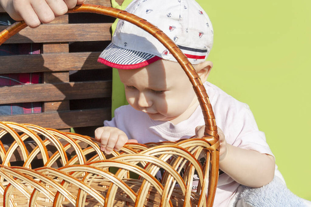 The baby looks into the wicker basket close-up - Foto, Imagen