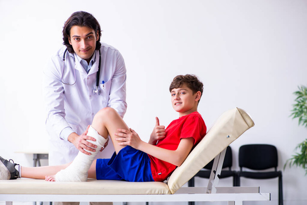 Perna ferido menino visitando jovem médico traumatologista
 - Foto, Imagem