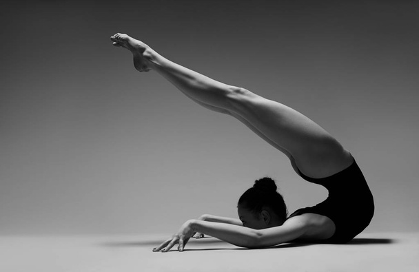 Gymnastka pózuje na podlaze. Černobílá fotografie. - Fotografie, Obrázek