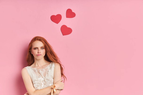 Woman with red hair on pink background with hearts - Zdjęcie, obraz
