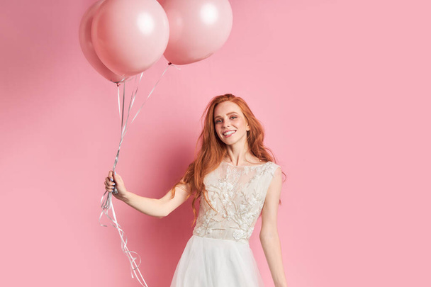 Smiling beautiful woman in dress of bride with pink air balloons - Photo, Image