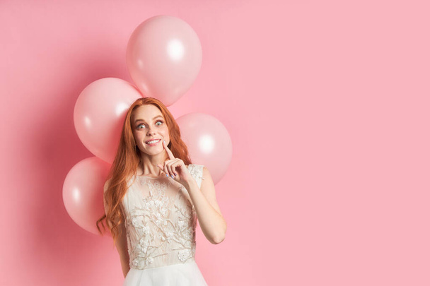Emotional redhead female in wedding dress on pink background - Foto, Imagem