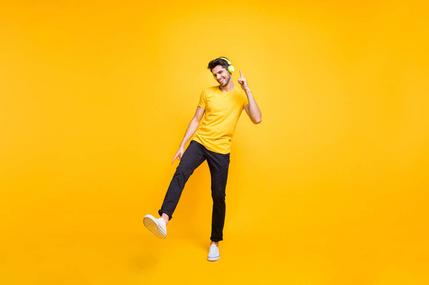 Pełna długość zdjęcie przystojnego faceta na studenckiej imprezie słuchanie muzyki młodych klapki tańczące ruchy młodzież nosić casual t-shirt spodnie odizolowany żółty kolor tło - Zdjęcie, obraz