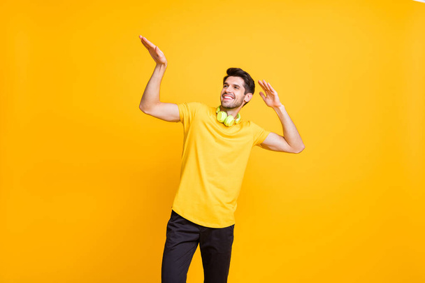 Photo of cheerful attractive handsome man dancing during weekend wearing yellow t-shirt black trousers smiling toothily having rest and fun isolated over vibrant color background - Foto, Imagen