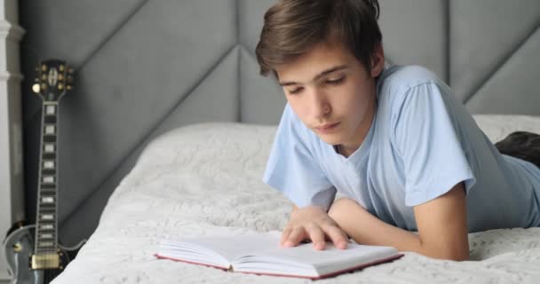 Young man sleeping with book at home  lying on bed. Teenage child tired after reading book. Teen boy  lies and resting on a sofa at afternoon . Real time. 4k footage.     - 映像、動画
