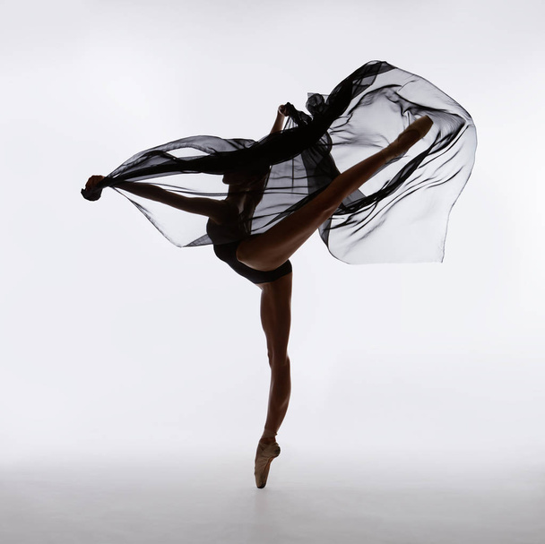 Bailarina em sapatos pontiagudos dançando com pano voador preto
 - Foto, Imagem