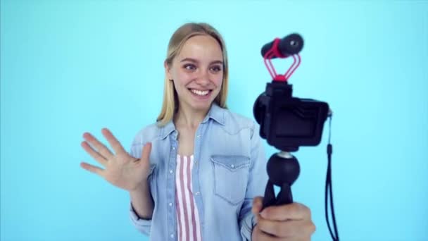 Beautiful girl blogger relieves itself at camera isolated blue background - Footage, Video