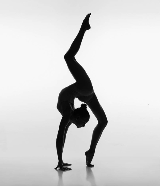 Flexibel meisje poseren in achtergrondverlichting - Foto, afbeelding