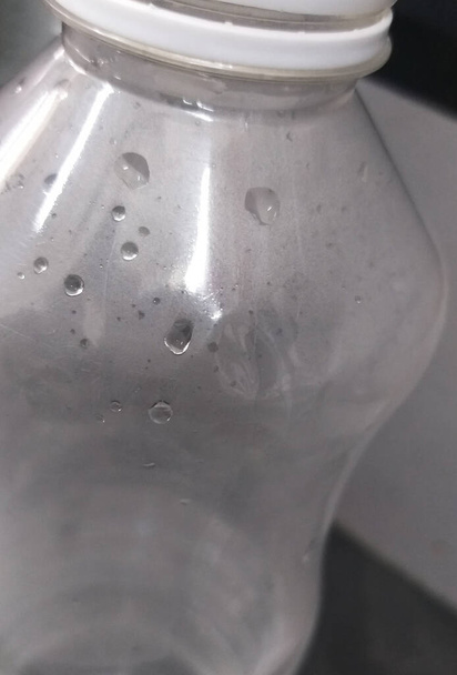 eine Nahaufnahme von Wassertropfen und Tau in einer Plastikwasserflasche. - Foto, Bild