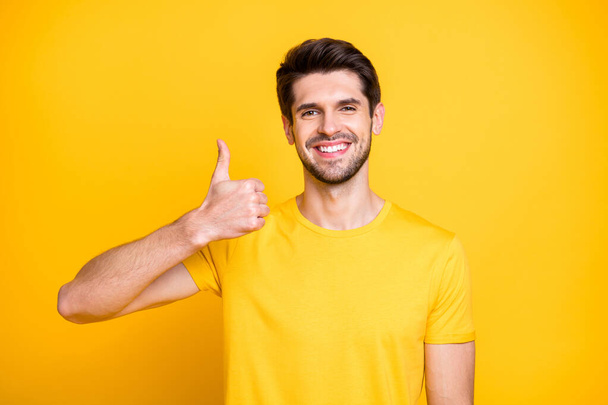 Close-up portrait of his he nice attractive cheerful cheery guy wearing tshirt showing thumbup ad advert solution isolated over bright vivid shine vibrant yellow color background - Foto, Imagen