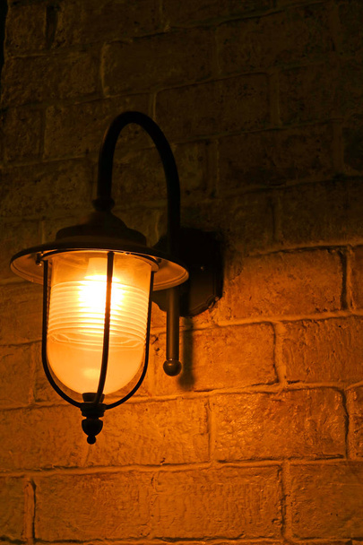 Vertical image of retro style lamp on the old brick wall - Photo, Image