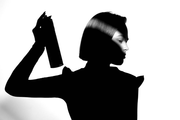 Black and white silhouette portrait with shadow and spot of light. The girl uses hairspray. Hair cosmetic concept. - Foto, Imagen