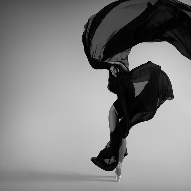 Siyah uçan kumaşla poz veren balerin. - Fotoğraf, Görsel